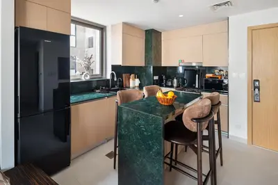 a kitchen with a black refrigerator and a counter with stools at Dubai Creek Poolside view Apartment - By DuStay in Dubai