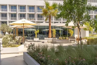 a hotel courtyard with tables and umbrellas in front of a building at New Charming Studio in JVC in Dubai