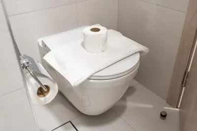 a white toilet with a roll of toilet paper on it at New Charming Studio in JVC in Dubai