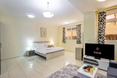 a hotel room with a bed and a tv at Livbnb-Spacious JVC Studio, Near Dining and Shops in Dubai