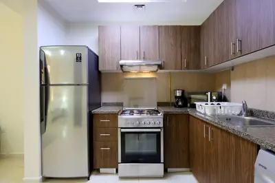 a kitchen with a stainless steel refrigerator and wooden cabinets at Livbnb-Spacious JVC Studio, Near Dining and Shops in Dubai
