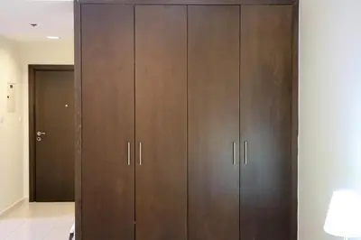 a large closet with wooden cabinets in a room at Livbnb-Spacious JVC Studio, Near Dining and Shops in Dubai