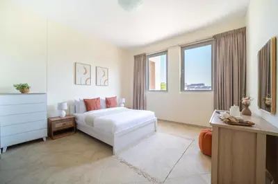 a white bedroom with a bed and two windows at Frank Porter - Widcombe House 3 in Dubai