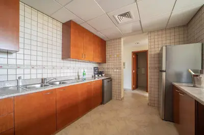 a kitchen with wooden cabinets and a stainless steel refrigerator at Frank Porter - Widcombe House 3 in Dubai