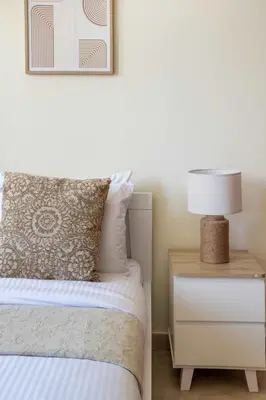 a bedroom with a bed and a nightstand with a lamp at Frank Porter - Widcombe House 3 in Dubai