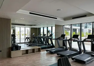a gym with a row of treadmills and mirrors at Modern 1BR Apartment in Binghatti Luna, Jumeirah Village Circle by Deluxe Holiday Homes in Dubai