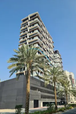 a tall building with palm trees in front of it at Modern 1BR Apartment in Binghatti Luna, Jumeirah Village Circle by Deluxe Holiday Homes in Dubai
