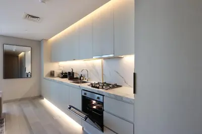 a kitchen with white cabinets and a stove top oven at Livbnb -Glam Studio in Marina Next to Marina Walk in Dubai