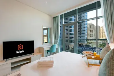 a hotel room with a tv and a large window at Exquisite Studio near Nakheel Mall by Livbnb in Dubai