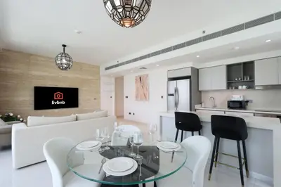 a dining room and kitchen with a glass table and chairs at Livbnb-Beachfront 3BR with Marina Harbour Panorama in Dubai