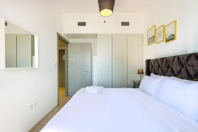 a bedroom with a large white bed and a mirror at Canalfront Gem 1BR in Zada Tower by Livbnb in Dubai