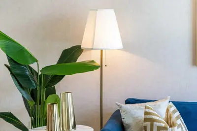 a lamp sitting next to a blue couch with a plant at Durrani Homes - The Luxe 3br with Burj Khalifa and Fountain View - third room without partition in Dubai