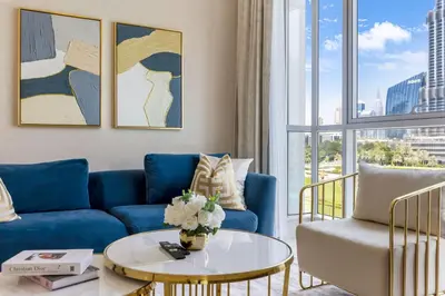 a living room with a blue couch and a table at Durrani Homes - The Luxe 3br with Burj Khalifa and Fountain View - third room without partition in Dubai