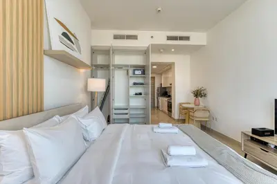 a bedroom with a white bed and a desk at Stylish Studio with Pool, Gym & Tasteful Decor in Dubai