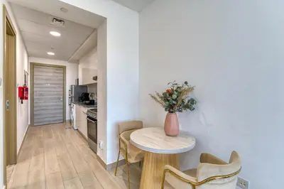 a kitchen with a table and a vase with flowers at Stylish Studio with Pool, Gym & Tasteful Decor in Dubai