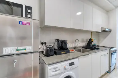 a kitchen with a sink and a dish washer at Stylish Studio with Pool, Gym & Tasteful Decor in Dubai