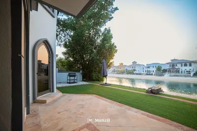 an outdoor patio with an umbrella next to a lake at Lux 5BR Villa with Pool & Beach Access in Palm Jumeirah in Dubai