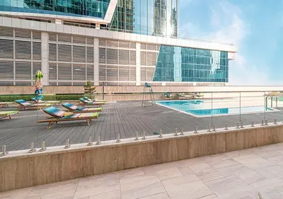a building with a swimming pool and some chairs at Brand new Studio in Business Bay, Missoni Tower in Dubai