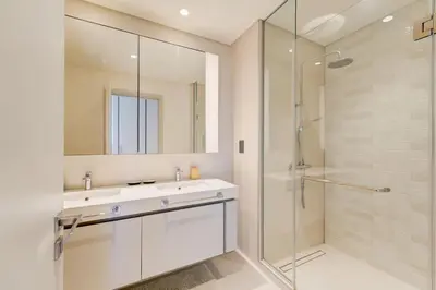 a bathroom with a sink and a shower with a mirror at Private Beachfront 2 Bed With 180 Marina Skyline in Dubai