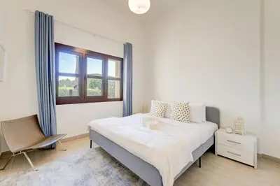 a white bedroom with a large bed and a chair at Serene 2-Bed Haven in Jumeirah Golf Estates in Dubai