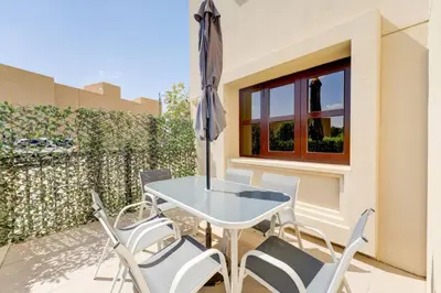 a patio with a table and chairs and an umbrella at Serene 2-Bed Haven in Jumeirah Golf Estates in Dubai