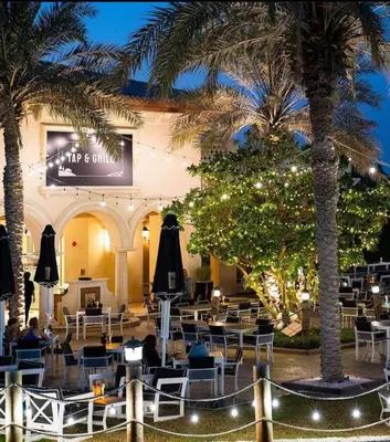 a restaurant with palm trees and tables and chairs at Serene 2-Bed Haven in Jumeirah Golf Estates in Dubai