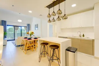 a kitchen with white cabinets and a island with bar stools at Serene 2-Bed Haven in Jumeirah Golf Estates in Dubai
