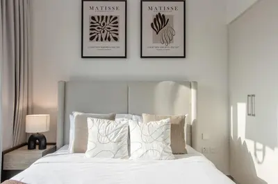 a bedroom with a white bed with three pictures on the wall at Livbnb - Stylish 1B in Park Heights Dubai Hills in Dubai