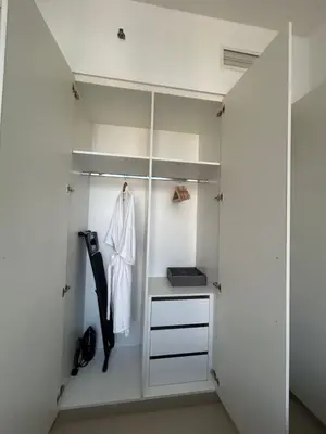 a walk in closet with white walls and white cabinets at Shared Apartment In Dubai Hills in Dubai