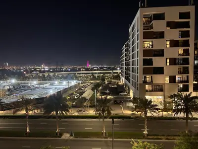a view of a city at night with a building at Shared Apartment In Dubai Hills in Dubai