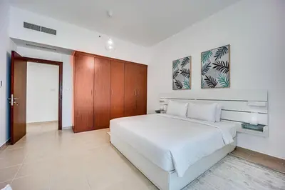 a bedroom with a large white bed and wooden cabinets at Bright apartment in JBR few steps from the beach in Dubai