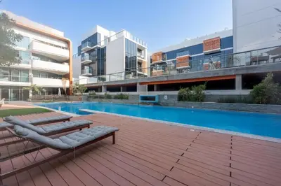 a swimming pool with two lounge chairs next to a building at HAVN - 1 Bedroom Apartment in Villa Pera, JVC in Dubai