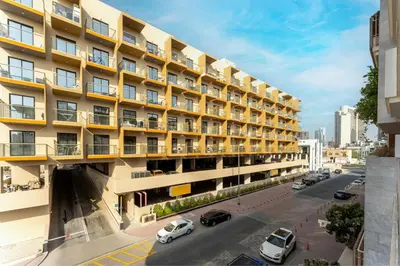 an apartment building with cars parked outside of it at HAVN - 1 Bedroom Apartment in Villa Pera, JVC in Dubai