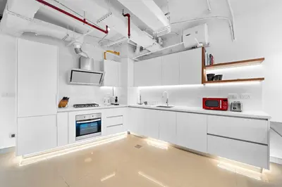 a white kitchen with white cabinets and a red appliance at Chic 1BR APT with Pool, Gym, BBQ, Tennis Court in Dubai
