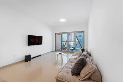 a living room with a couch and a tv at Chic 1BR APT with Pool, Gym, BBQ, Tennis Court in Dubai