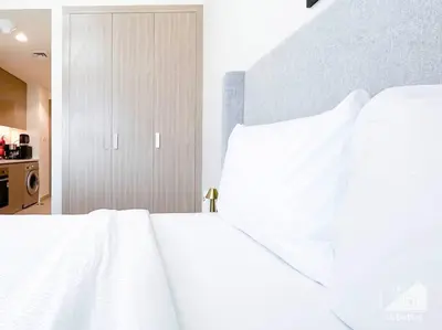 a bedroom with a bed with white sheets and a closet at Balcony Studio Haven in Riviera in Dubai