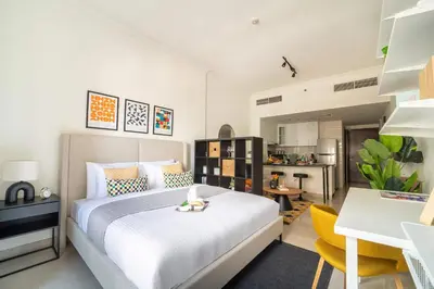 a bedroom with a white bed and a kitchen at Frank Porter - G24 Tower in Dubai