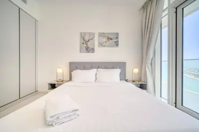 a white bedroom with a large bed and large windows at New 2 bedroom full sea view in Dubai
