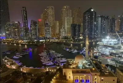 a city at night with boats in the water at Brand New and Stylish Interior in Dubai