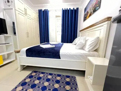 a bedroom with a large bed with blue curtains at Brand New and Stylish Interior in Dubai