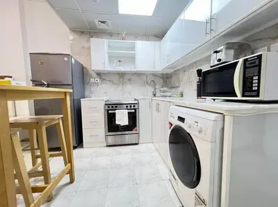 a kitchen with a washing machine and a microwave at Brand New and Stylish Interior in Dubai