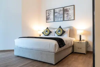 a bedroom with a large white bed with two lamps at Vogue Al Fahad Tower, Al Barsha Heights near Mall of The Emirates, Walking Distance to DIC Metro Station, Two Bedroom Apartment with Balcony and Access to all Amenities in Dubai