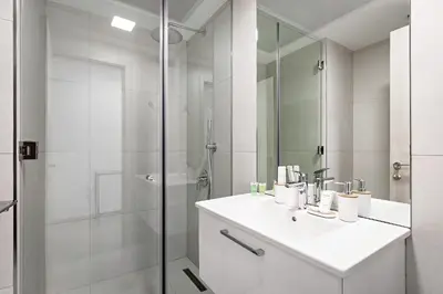 a white bathroom with a sink and a shower at Bright 1BR with balcony in Luma 22 in Dubai