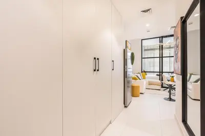 a hallway with white cabinets and a living room at Stylish Contemporary Home in JVC with Chic Interior in Dubai