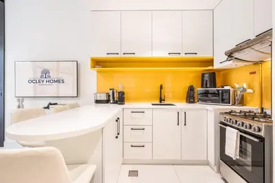 a kitchen with white cabinets and a yellow wall at Stylish Contemporary Home in JVC with Chic Interior in Dubai