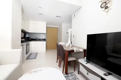a kitchen and dining room with a table and a television at Chic Aykon City 2-Bedroom Retreat - Business Bay in Dubai
