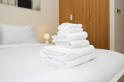 a pile of towels stacked on top of a bed at Urban Oasis - Cosy Studio Retreat in Dubai