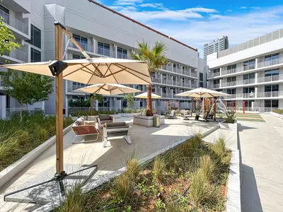 a courtyard with chairs and umbrellas in a building at Cozy & Bright Home in the Heart of JVC in Dubai