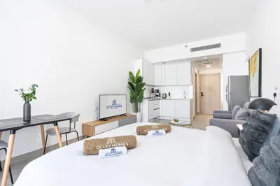 a living room with a large bed and a kitchen at Cozy & Bright Home in the Heart of JVC in Dubai