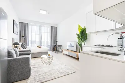 a kitchen and a living room with a couch at Cozy & Bright Home in the Heart of JVC in Dubai